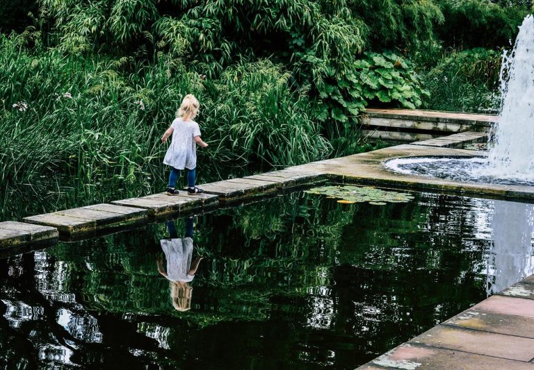 Mooi ingerichte tuin netjes met speeltoestellen, houten schommel en georganiseerde speelzone tussen groen